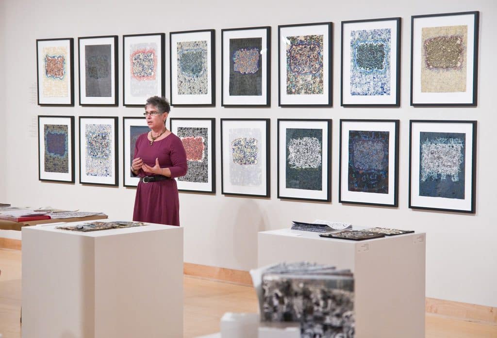 A woman standing in front of a wall with many pictures on it.