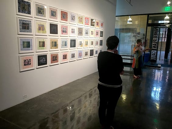 A woman standing in front of a wall with many pictures on it.