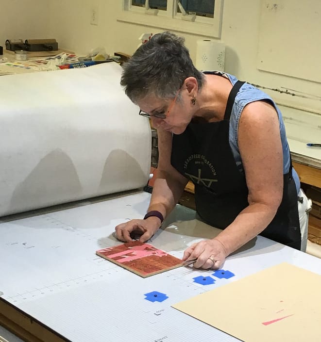 A woman is cutting paper on top of a table.